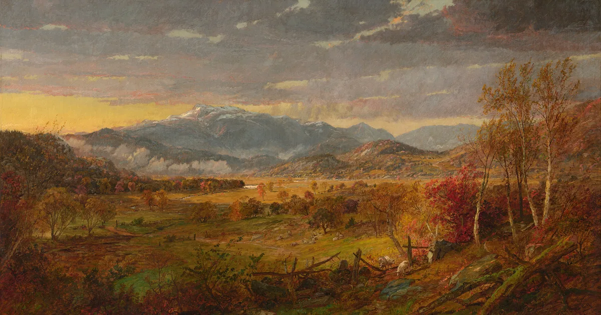 An autumn valley crossed by paths, a snow-capped mountain in the distance under a storm sky broken by light