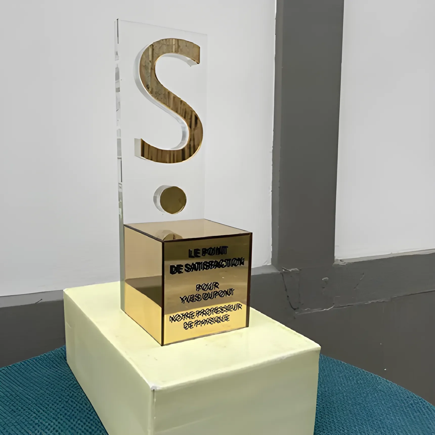 Gold trophy engraved with the French words for the satisfaction mark, for Yves Dupont, our physics teacher