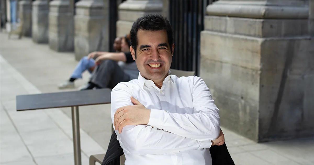 Warith Harchaoui, arms crossed, in front of a colonnade